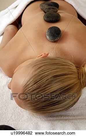 Stock Image - Young woman enjoying a hot stone massage. Fotosearch