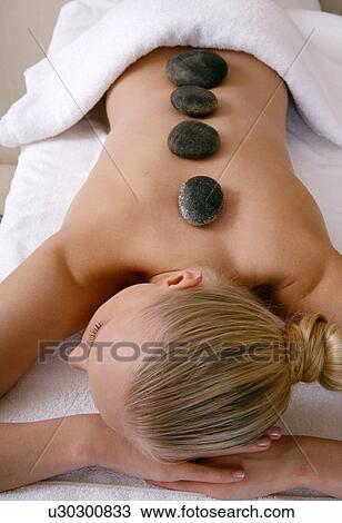 Stock Image - Young woman enjoying a hot stone massage. Fotosearch