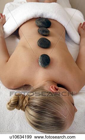 Young woman enjoying a hot stone massage View Large Photo Image Stock Photo - Young woman enjoying a hot stone massage. Fotosearch