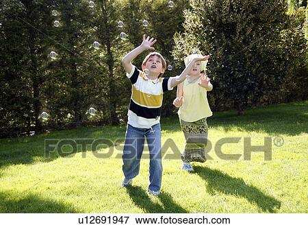 Stock Photo - Children playing with bubbles. Fotosearch