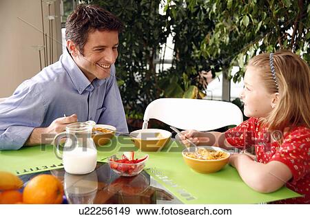 Stock Photo - Father and children eating breakfast. Fotosearch