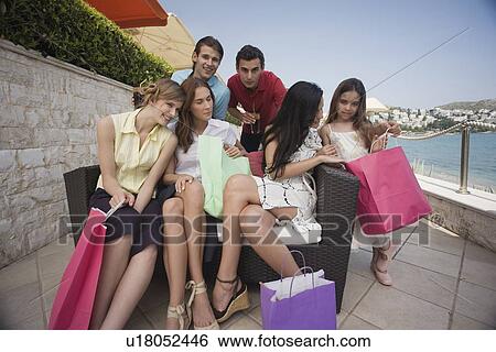 Stock Photograph - Group of friends with shopping bags posing. Fotosearch