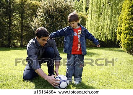 Picture - Man teaching boy to play soccer. Fotosearch