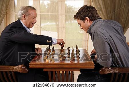 Stock Photograph - Mature man and younger man playing chess. Fotosearch