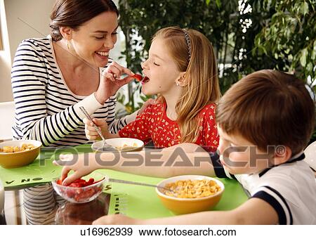 Stock Photo - Mother and children eating breakfast. Fotosearch
