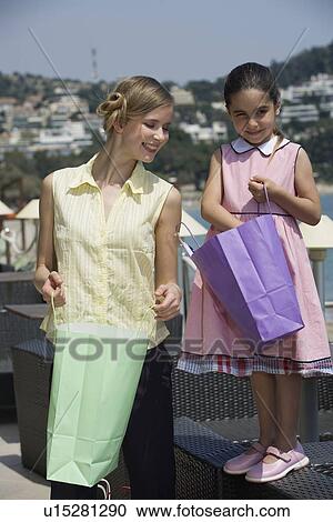 Stock Image - Mother and daughter looking in shopping bags. Fotosearch