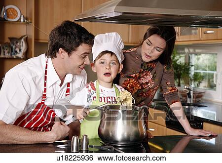 Stock Photograph - Parents and son cooking spaghetti. Fotosearch