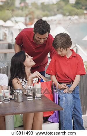 Stock Image - Parents and son with shopping bags at a cafe. Fotosearch