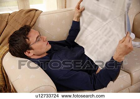 Picture - Young man reading a newspaper. Fotosearch