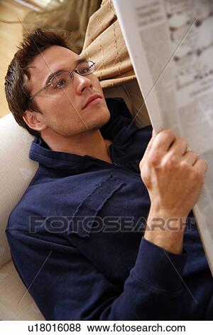 Young man reading a newspaper View Large Photo Image Stock Photo - Young man reading a newspaper. Fotosearch
