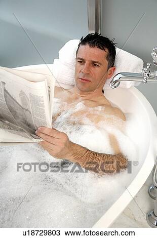 Stock Image - Man relaxing in bathtub with bubbles. Fotosearch