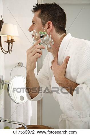 Stock Image - Man shaving in front of mirror. Fotosearch