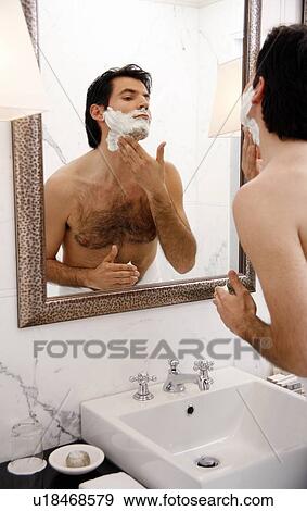 Stock Photo - Man shaving in the bathroom mirror. Fotosearch