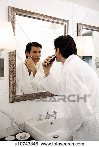 Stock Photograph - Man shaving in the bathroom mirror. Fotosearch