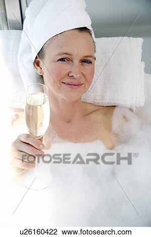 Stock Image - Mature woman enjoying bubble bath. Fotosearch