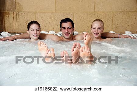 Stock Image - One man with two women in jacuzzi at a spa. Fotosearch