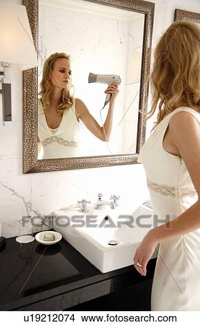 Picture - Woman brushing hair in bathroom. Fotosearch