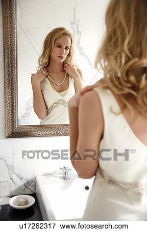 Woman looking at herself in the bathroom mirror View Large Photo Image Stock Photo - Woman looking at herself in the bathroom mirror. Fotosearch