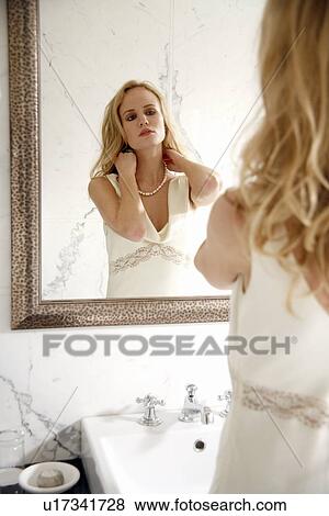 Woman looking at herself in the bathroom mirror View Large Photo Image Stock Photo - Woman looking at herself in the bathroom mirror. Fotosearch