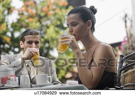 Business couple in garden cafe drinking orange juice View Large Photo Image Stock Photo - Business couple in garden cafe drinking orange juice. Fotosearch
