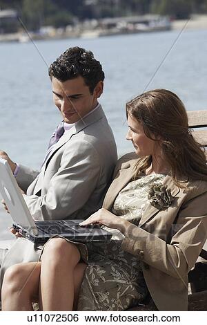 Stock Photograph - Business couple on beach with fishing rod and laptop. Fotosearch