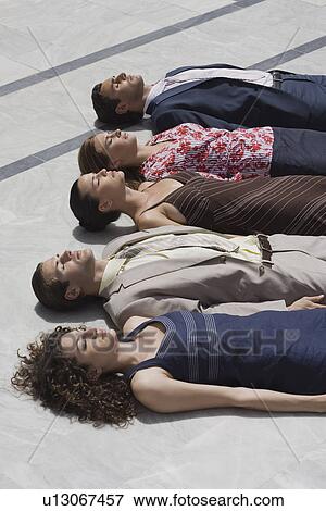 Business people lying on the ground in a row View Large Photo Image Stock Photo - Business people lying on the ground in a row. Fotosearch