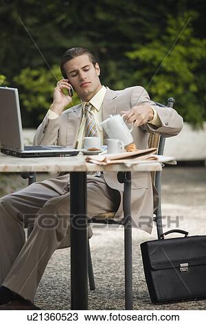 Businessman in garden cafe with cell phone and laptop View Large Photo Image Stock Image - Businessman in garden cafe with cell phone and laptop. Fotosearch