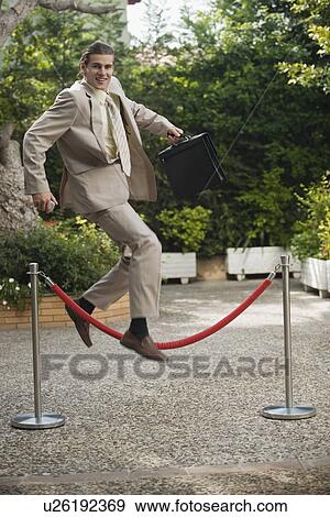 Businessman in garden jumping over barrier View Large Photo Image Stock Photo - Businessman in garden jumping over barrier. Fotosearch