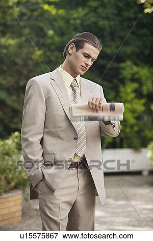 Stock Photo - Businessman in garden looking at watch. Fotosearch