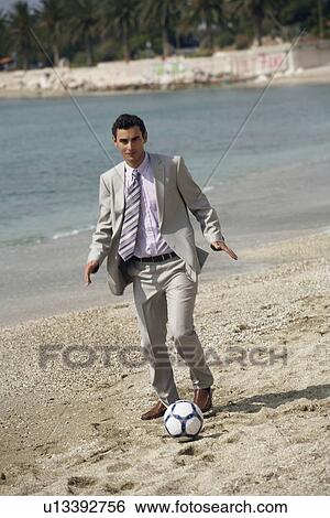 Stock Photograph - Businessman on beach playing soccer. Fotosearch