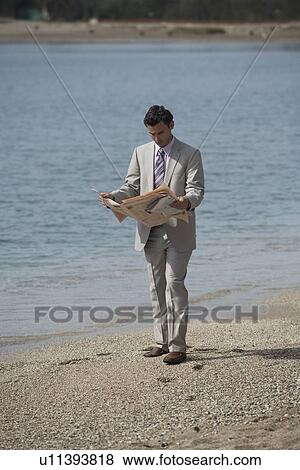 Businessman on beach reading a newspaper View Large Photo Image Stock Photo - Businessman on beach reading a newspaper. Fotosearch