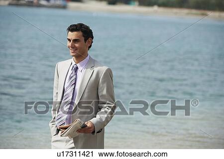 Stock Image - Businessman on beach with a newspaper. Fotosearch