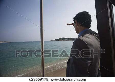 Stock Photo - Businessman on life guard looking out to sea. Fotosearch