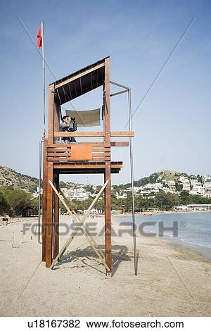 Stock Image - Businessman on life guard stand with binoculars. Fotosearch
