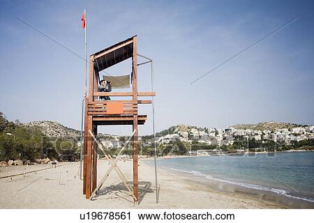 Stock Image - Businessman on life guard stand with binoculars. Fotosearch