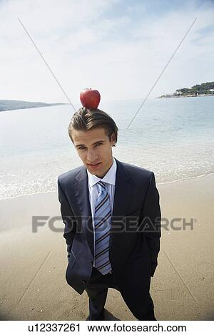 Stock Image - Businessman with apple balanced on his head. Fotosearch