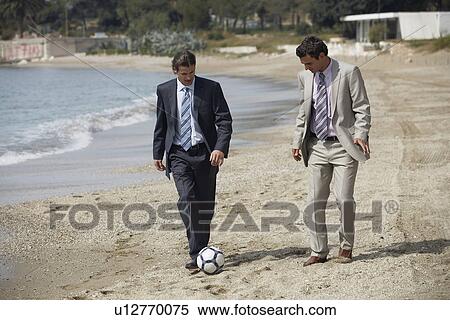 Stock Photography - Businessmen on beach playing soccer. Fotosearch