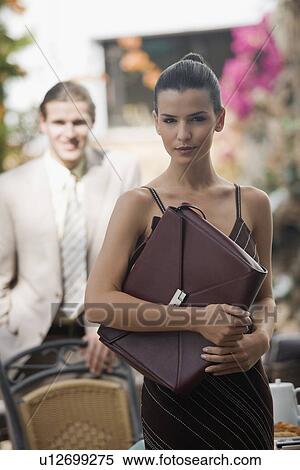 Stock Photography - Businesswoman in garden with businessman in background. Fotosearch