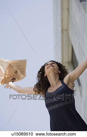 Stock Image - Happy businesswoman throwing newspaper in the air. Fotosearch
