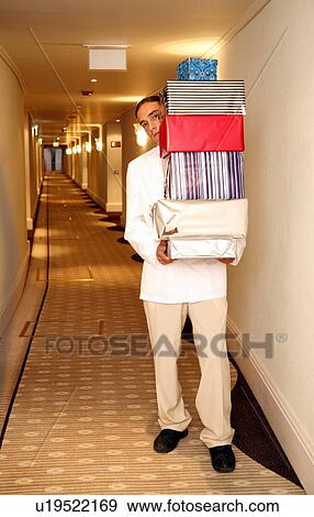 Bellboy carrying gift boxes down hallway View Large Photo Image Stock Photo - Bellboy carrying gift boxes down hallway. Fotosearch
