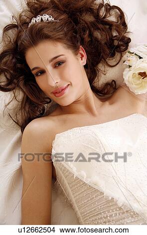 Picture - Bride lying down on wedding bed. Fotosearch