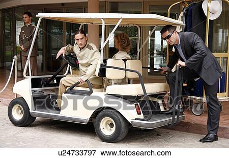 Couple being driven in cart by hotel bellboy View Large Photo Image Stock Photo - Couple being driven in cart by hotel bellboy. Fotosearch