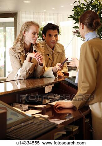 Couple checking in at hotel reception View Large Photo Image Stock Photography - Couple checking in at hotel reception. Fotosearch