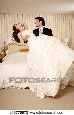 Groom holding bride in his arms in hotel room View Large Photo Image Stock Image - Groom holding bride in his arms in hotel room. Fotosearch