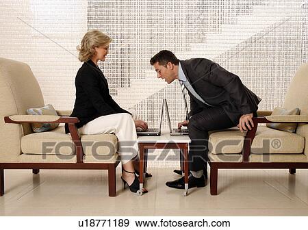 Stock Photo - Man and woman sitting in hotel lobby. Fotosearch