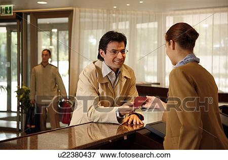 Stock Photo - Man checking in at the hotel reception desk. Fotosearch