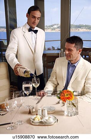 Stock Image - Waiter serving customer in restaurant. Fotosearch