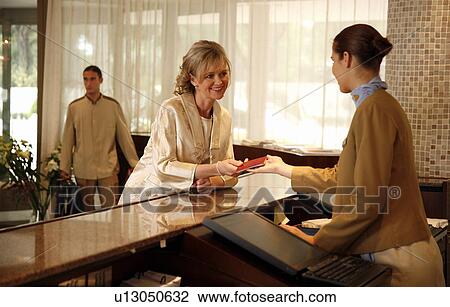 Woman checking in at the hotel reception desk View Large Photo Image Stock Image - Woman checking in at the hotel reception desk. Fotosearch