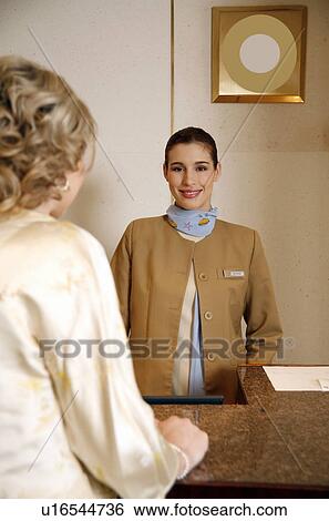 Stock Photograph - Woman checking in at the hotel reception desk. Fotosearch