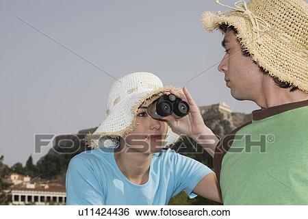 Stock Photograph - Couple at archaeological site with hats and binoculars. Fotosearch